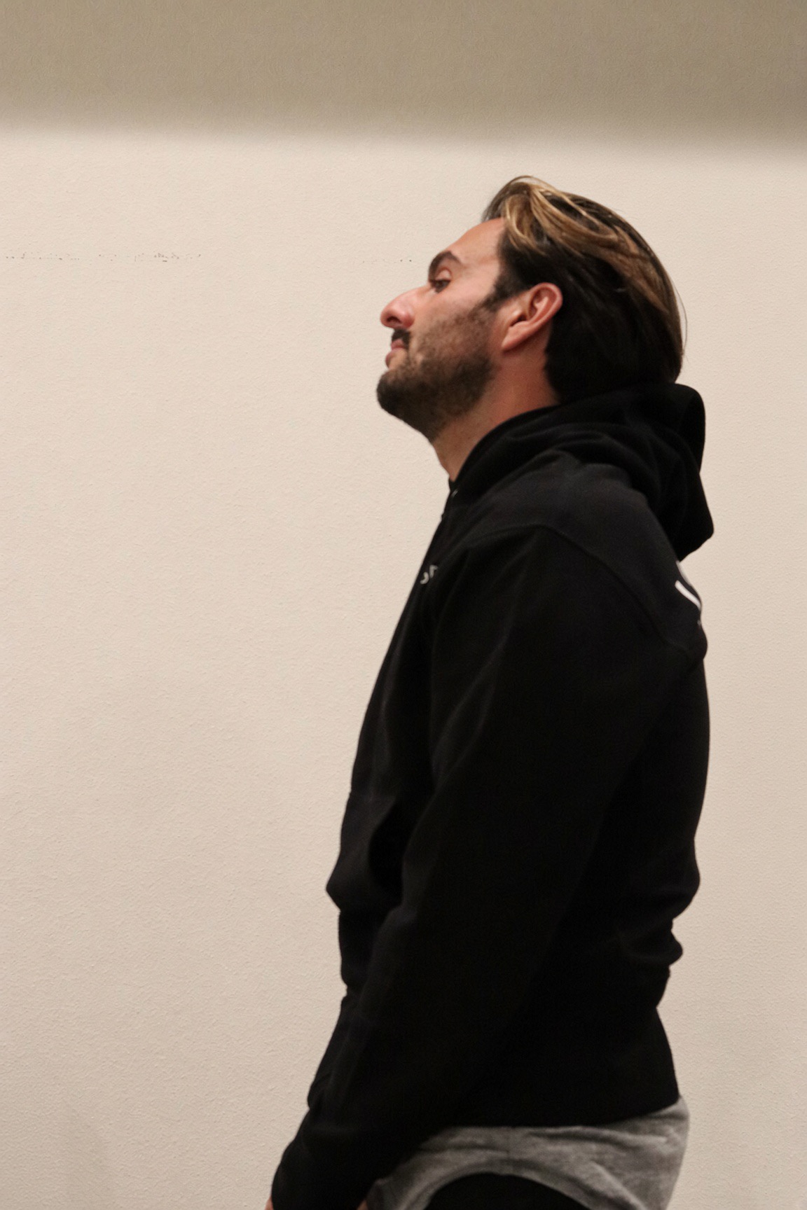 Coach in profile, wearing a black hoodie